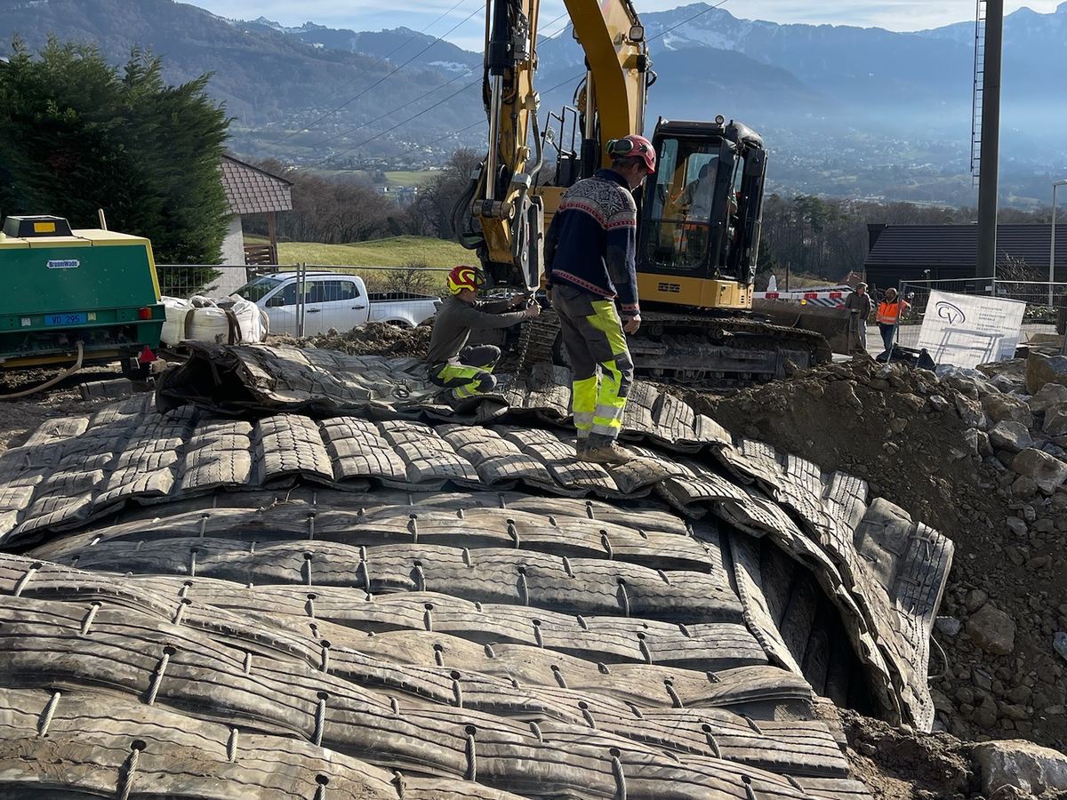 Zone de tir recouverte de matelas pare-éclats, pelle et montagnes derrière